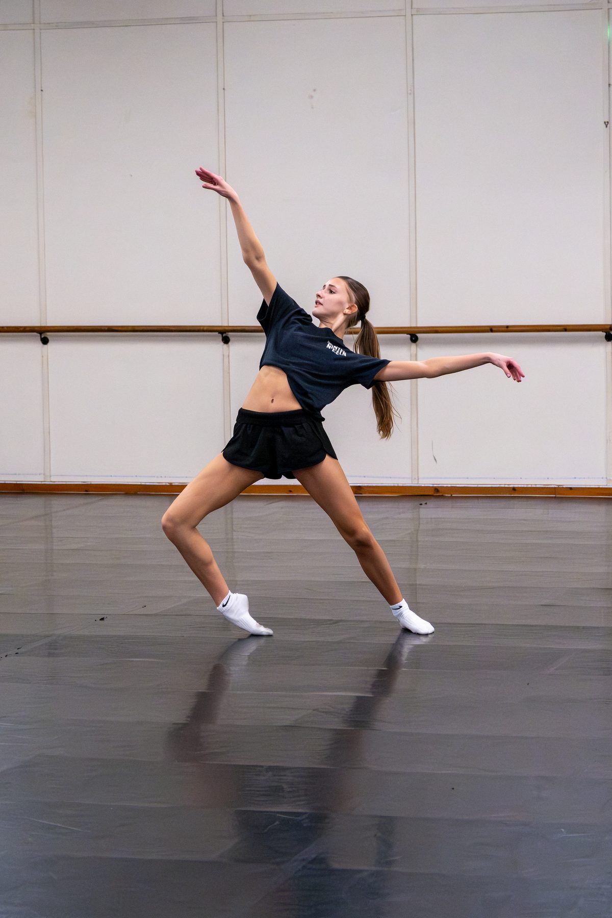 A senior dancer in a deep contemporary floor stretch during an intensive